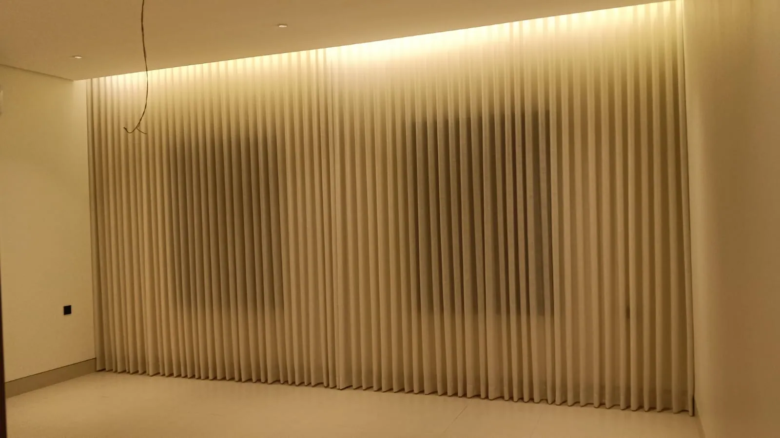 Full-height wave curtains along a long villa hall wall in Dammam